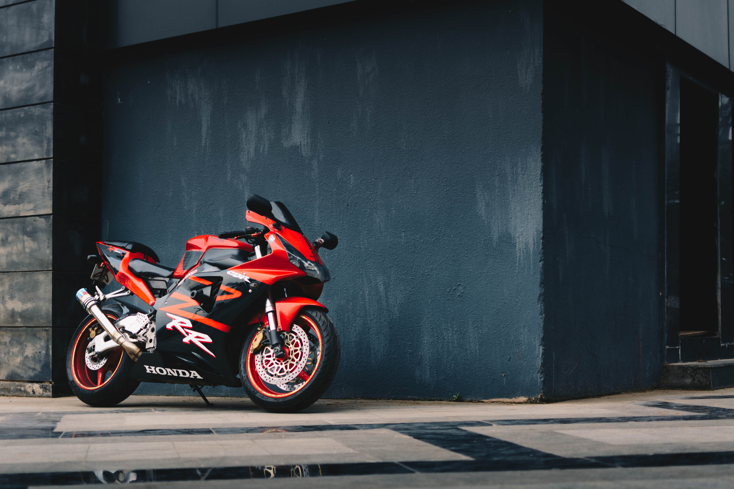 Photo of Red and Black Honda Sport Bike Parked Next to Black Wall